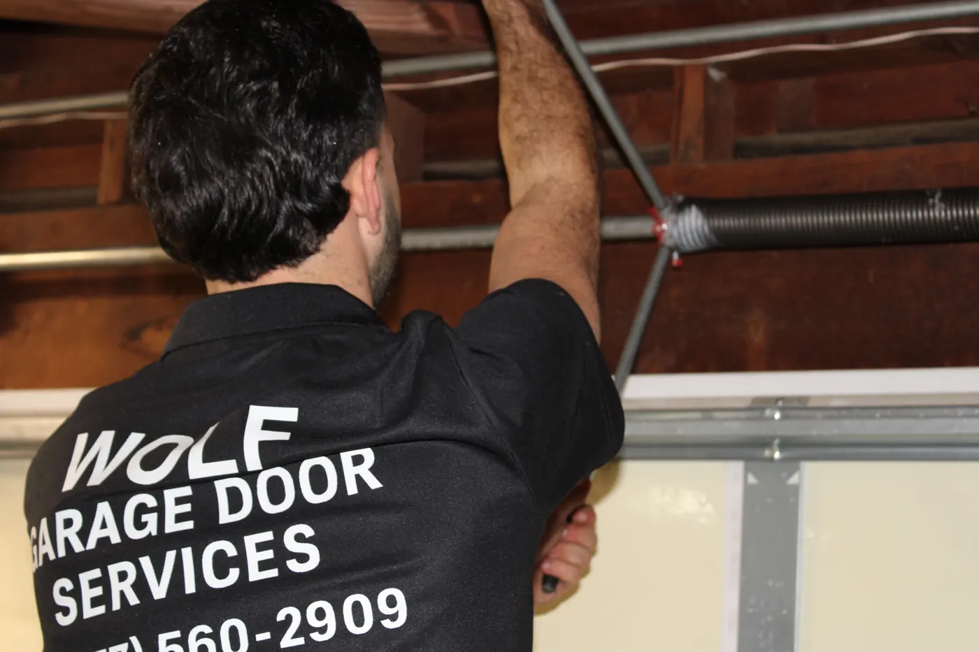 Wolf technician winding a torsion spring, company name on his shirt